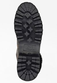 Semelle en caoutchouc noir avec des bandes profondes pour une traction optimale, logo en relief et un bord arrondi texturé. Conçue pour la durabilité et l'adhérence.