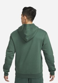 Felpa verde scuro con tasca a marsupio frontale, cappuccio con coulisse e polsini e orlo a coste. Tessuto morbido con una texture liscia.