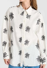 White button-up shirt in a lightweight fabric, featuring black palm tree patterns, classic collar, and long sleeves with buttoned cuffs.