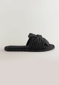 Black fabric slipper with a striped pattern, knot detail on the upper, and a padded sole. Features a smooth texture and a rounded shape.
