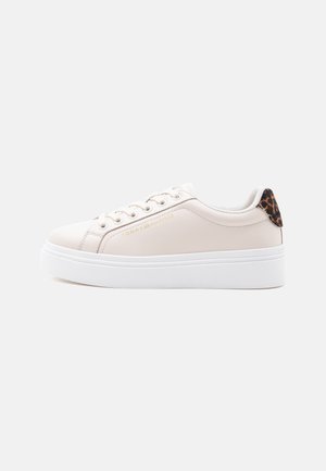 Zapatilla de plataforma color crema con suela blanca, logo dorado "Tommy Hilfiger" en el lateral y detalle de estampado de leopardo en el cuello del talón.