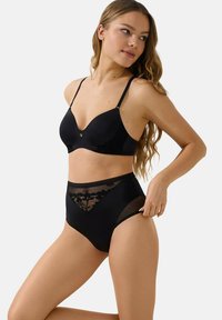 Ensemble de lingerie noire comprenant un soutien-gorge à bonnets lisses avec des accents en dentelle et un slip taille haute. Des panneaux en maille mettent en valeur des motifs floraux.