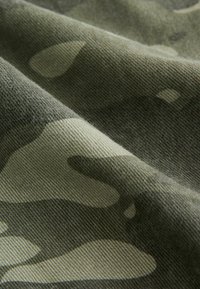 Kamo látka v odtieňoch zelenej, s mäkkým, textúrovaným povrchom a abstraktnými vzormi v rôznych odtieňoch olivovej a tmavozelenej.