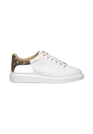 Zapatilla de piel blanca con punta redondeada, suela plana y acentos marrones con patrón en el talón. Ojetes de metal y cordones planos completan el diseño.