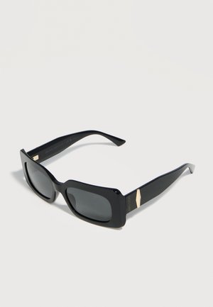 Gafas de sol rectangulares negras con lentes oscuras y detalles dorados en las patillas gruesas, mostradas sobre un fondo claro.