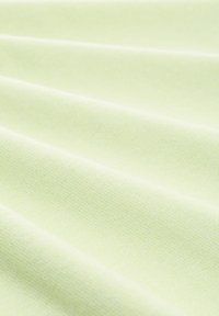 Lichtgroene stof met een zachte textuur, met een glad, licht gestructureerd oppervlak en zachte plooien die de buigzame aard benadrukken.