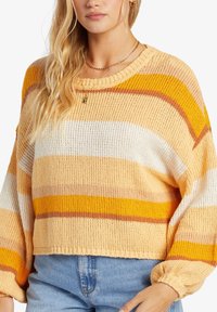 Skrócony sweter z dzianiny w pomarańczowo-żółte paski, z okrągłym dekoltem i luźnymi rękawami. Teksturowana tkanina o luźnym kroju.