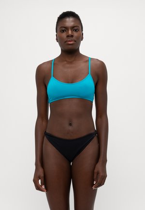 Világoskék bikini felső vékony pántokkal és kerek nyakkivágással, fekete bikini alsóval párosítva. Sima textúra, minimalista dizájn.