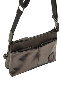 Borsa a tracolla grigia con texture, dotata di tasche con zip, cinturino regolabile e un accento del logo nell'angolo in basso a destra. Design compatto e pratico.