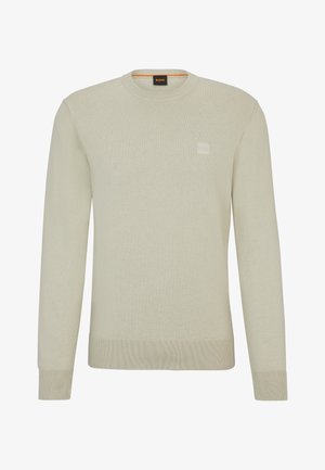 Suéter de punto beige claro con cuello redondo, mangas largas y un acabado texturizado. Presenta una pequeña etiqueta de logo en el pecho.