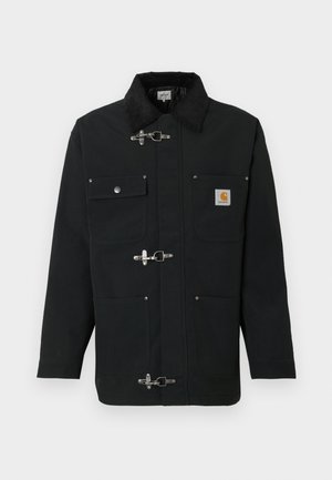 Giacca nera in tessuto pesante, con colletto in velluto a coste, quattro tasche frontali e chiusure a molla metalliche. Logo Carhartt sul petto.