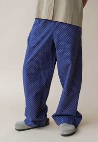 Himmelblaue, weit geschnittene Hose mit einem weißen Punktemuster, aus leichtem Stoff mit glatter Textur.