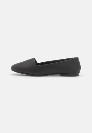 Zapatos planos negros hechos de cuero sintético texturizado. Presentan una punta afilada y un diseño minimalista con una suela baja y flexible.