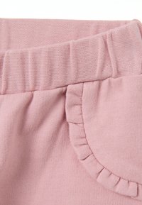 Lichtroze katoenen stof met een elastische tailleband en ruches op de zakdetails, met een gladde textuur en subtiele rek.