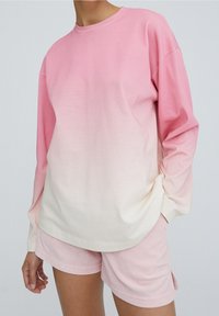 Pitkähihainen liukuvärjätty svetari vaaleanpunaisissa sävyissä pehmeästä puuvillakankaasta, yhdistetty saman sävyisiin vaaleanpunaisiin samettisiin shortseihin.