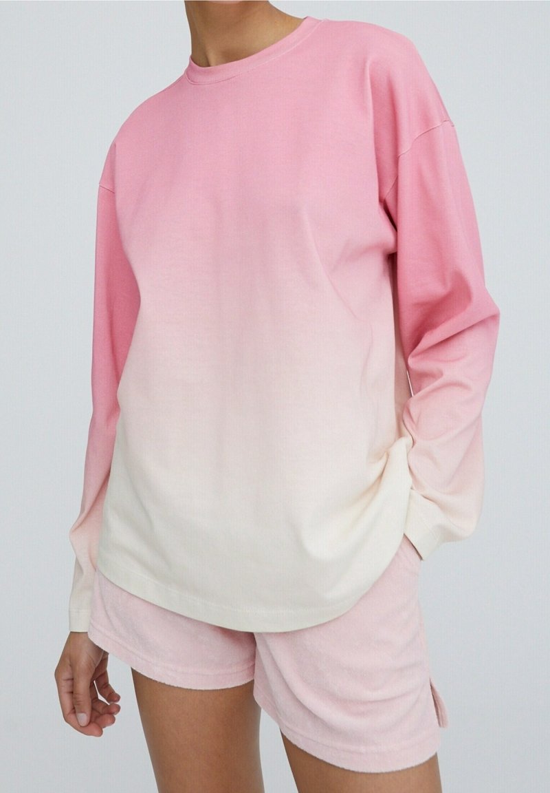 Pitkähihainen liukuvärjätty svetari vaaleanpunaisissa sävyissä pehmeästä puuvillakankaasta, yhdistetty saman sävyisiin vaaleanpunaisiin samettisiin shortseihin.