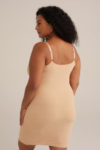 Bežové bodycon šaty s tenkými ramienkami, rovnou výstrihom, hladkým povrchom a okrúhlymi kovovými detailmi na ramienkach.