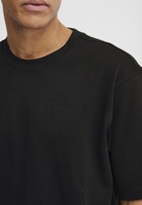 Svart bomulls T-skjorte med rund hals og korte ermer, med en glatt tekstur og minimalistisk design uten synlige logoer eller mønstre.