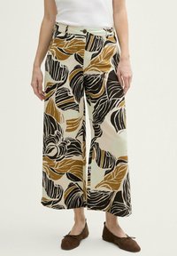 Pantalons évasés à jambes larges en tissu léger, ornés d'un motif de feuilles audacieux en noir, marron et crème. Comprend une fermeture à bouton à l'avant et des poches.