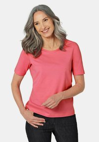 Roze T-shirt met korte mouwen, gemaakt van zachte stof, met een ronde halslijn en een losse pasvorm, gecombineerd met donkerblauwe jeans.