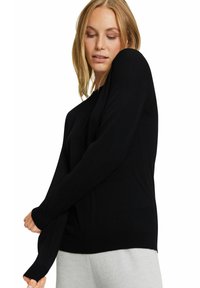 Schwarzer Langarmpullover aus weichem Stoff. Verfügt über einen lockeren Schnitt, gerippte Bündchen und einen runden Halsausschnitt. Einfaches, klassisches Design.
