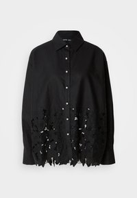 Camisa de algodão preta com gola, fecho frontal por botões e detalhes em rendas florais intrincadas na bainha. Ajuste relaxado com mangas longas.