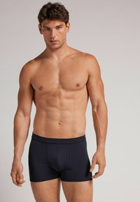 Granatowe bokserki wykonane z gładkiego materiału, charakteryzujące się dopasowanym krojem, płaskimi szwami i wygodnym pasem. Prosty design bez wzorów.