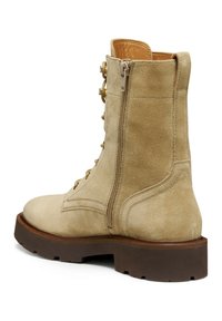 Stivale in suede beige con lacci e zip laterale, punta tonda, superficie texturizzata e suola in gomma marrone robusta. Sottiglie cuciture decorative sui lati.