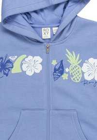 Světle modrá zipová mikina s kapucí, zdobená květinovým a tropickým vzorem v tmavě modré, bílé a zelené barvě. Obsahuje přední kapsy.
