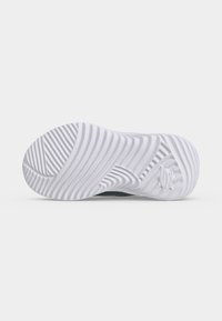 Semelle de basket blanche avec des rainures courbées et angulaires pour l'adhérence, avec un logo Skechers en relief près du talon, vue de dessous.