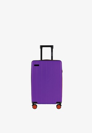 Hardshellkoffer in levendig paars. Voorzien van horizontale groeven, een uitschuifbare zwarte handgreep en vier wielen met rode accenten voor mobiliteit.