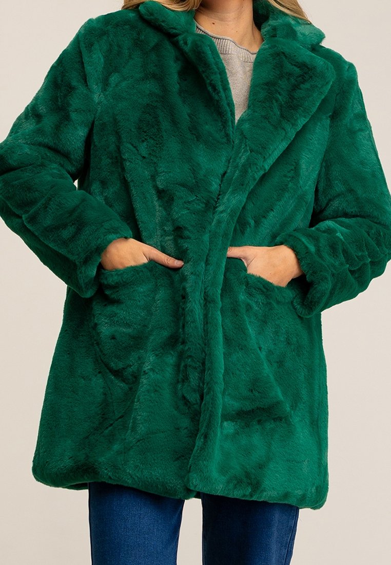 Cappotto in faux fur verde con colletto a punta, tasche frontali e texture morbida, caratterizzato da una vestibilità rilassata e da un design di lunghezza intermedia.