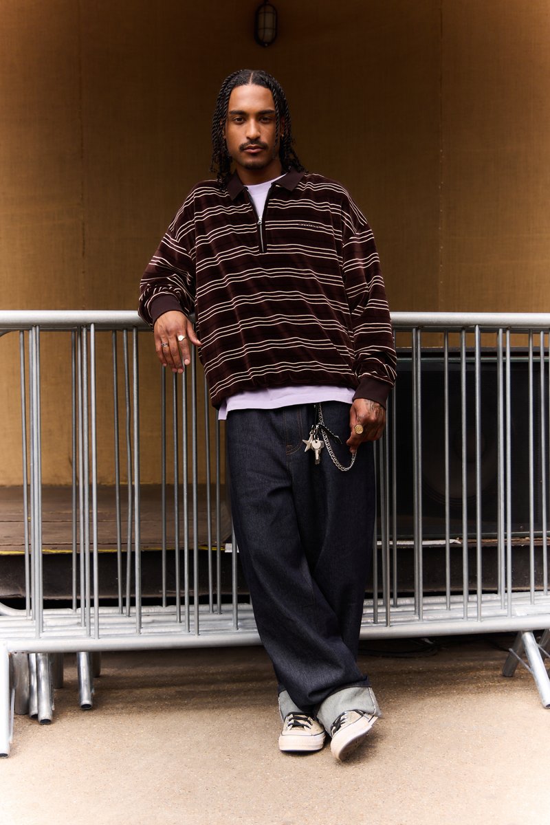 Brun- och cremefärgad fleecepullover med halv dragkedja, kombinerad med lösa jeans och canvas-sneakers. Nycklar fästa med en kedja.