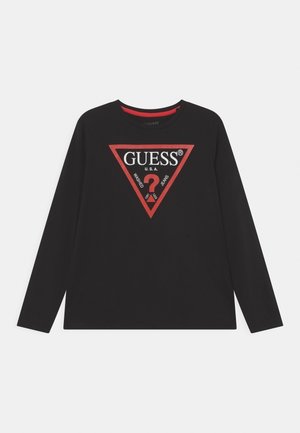 Chemise noire à manches longues avec un logo triangulaire bordé de rouge portant l'inscription "GUESS U.S.A." et un grand point d'interrogation rouge au centre.