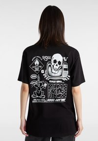 Camiseta negra con diseños gráficos en blanco en la parte posterior, que incluyen una calavera, un personaje de conejo y elementos de texto con diversas formas y patrones.