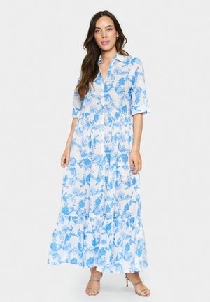 Abito lungo con fantasia floreale blu e bianca, maniche corte, apertura frontale con bottoni, design a strati e tessuto leggero.