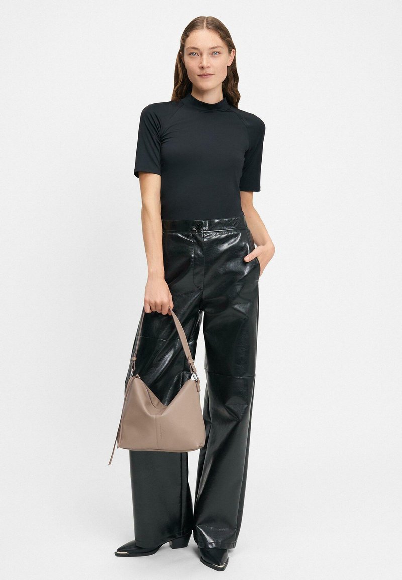 Schwarzes kurzärmeliges Oberteil, hochtaillierte glänzende schwarze Kunstlederhose und eine beigefarbene samtige Handtasche mit Gurt. Einfaches Design und klare Linien.