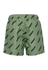 Gröna shorts gjorda av ett slätt tyg med ett mönster av det svarta "HUMMEL"-logotypen över hela ytan. Elastisk midja för bra passform, avsydda kanter.