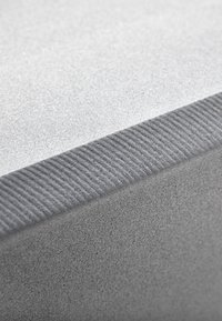 Gray textured surface with a smooth, soft finish bordered by a ribbed edge, emphasizing contrasts in texture and subtle color variations.