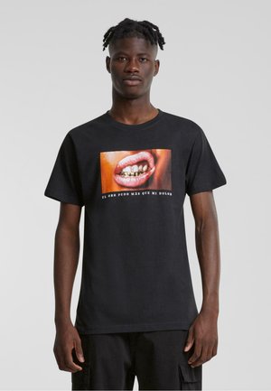Sort bomuld t-shirt med et farverigt grafik af en mund med gyldne tandgrill og spansk tekst nedenfor. Korte ærmer, klassisk pasform.