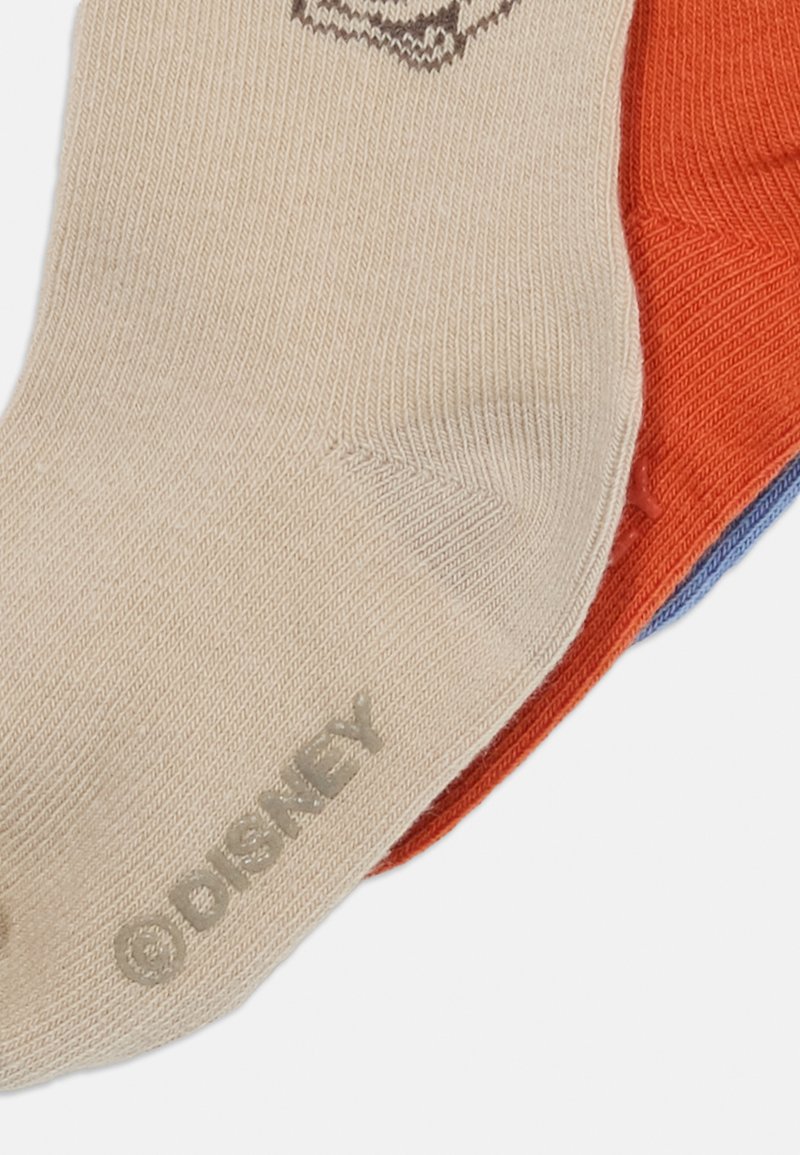 Beige, rote und blaue Socken aus strukturiertem Baumwollgemisch, mit einem auf der Sohle der beigen Socke aufgedruckten Disney-Logo.