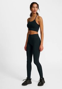 Svart atletisk crop top och högmidjade leggings av stretchtyg, med sömlös design och minimal detaljering.