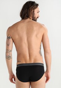 Svarta herrboxershorts med en kontrasterande grå midjeelastisk, tillverkade av mjukt tyg, med en tajt passform och minimalistisk design.