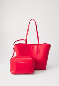 Bolsa tote de couro vermelho com duas alças, acabamento liso, e uma pequena bolsa com fecho com zíper correspondente, apresentando um logótipo.