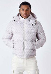 Giacca a vento leggera di colore grigio chiaro con motivo a logo in rilievo, colletto alto, zip frontale e tasche laterali. Presenta una texture imbottita e una vestibilità aderente.