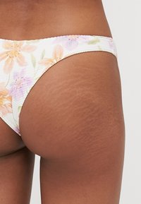 Virágmintás bikini alsó bordázott anyagból; pasztell színű virágokkal fehér háttérrel, vékony elasztikus derékpánttal.