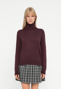 Burgundin turtleneck-neule, jossa on pitkät hihat, valmistettu pehme�ästä materiaalista. Yhdistetty musta-valkoiseen ruudulliseen pleat-hameeseen. Yksinkertainen muotoilu.