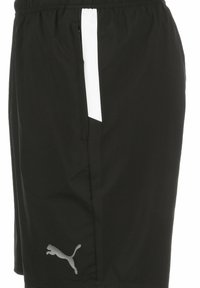 Schwarze Sportshorts mit einem elastischen Bund, ausgestattet mit einem weißen Seitenstreifen und einem kleinen grauen Logo an der unteren Vorderseite. Glatte Textur.