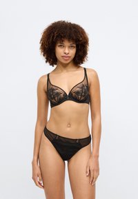 Czarny biustonosz koronkowy z pasującym zestawem majtek bikini z przezroczystymi panelami, kwiatowymi wzorami, cienkimi ramiączkami i dekoracyjnymi akcentami metalowymi.