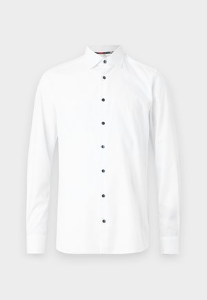 Balta ilga rankovė marškiniai su sagų apykakle, puošti juodomis sagomis ir lygiu paviršiumi. Jokių raštų ar grafikų nematyti.